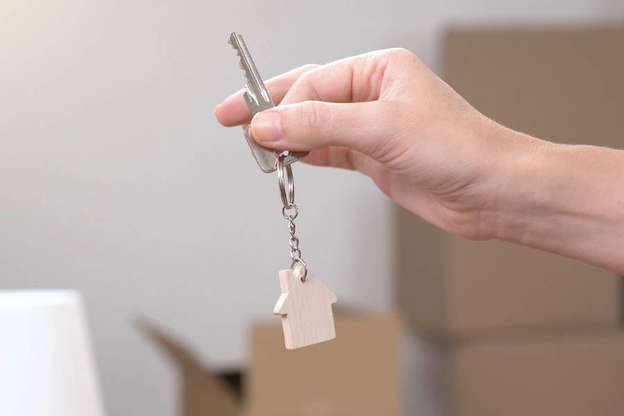 Someone holding a key, or handing a key to someone, illustrating a mortgage guarantor